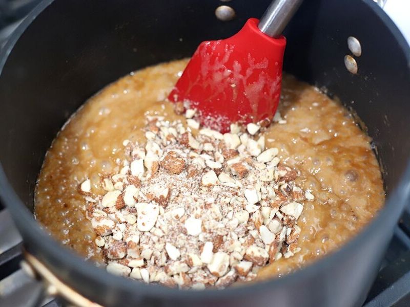 Almond being added to caramel for candy