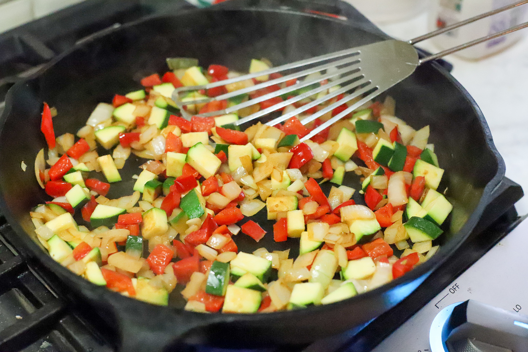 onions, peppers, and zucchini in frying pan