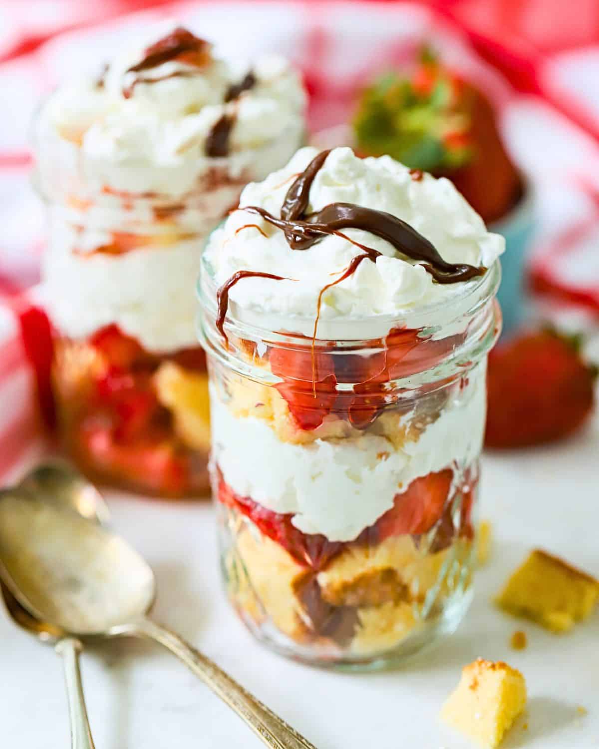 Jar full of strawberry shortcake with whipped cream on top.