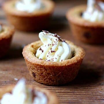 A chocolate chips cookie cups on a counter with shaved chocolate on top.