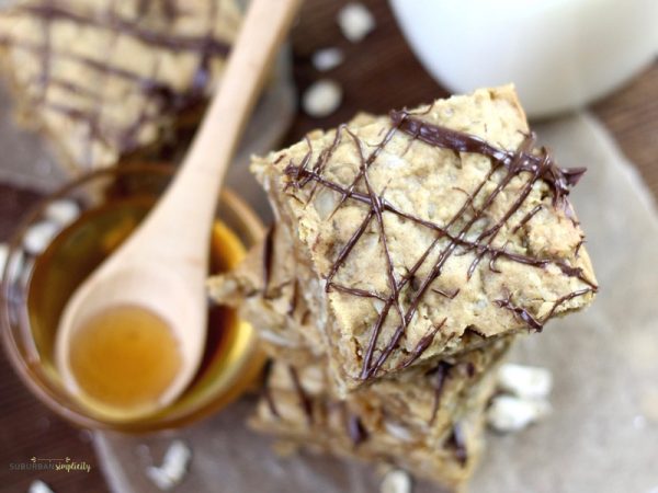 Peanut Butter Oatmeal squares stacked with a bowl of honey next to it.