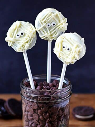 Three Mummy Oreo Cookies Pops sticking out of a glass jar.