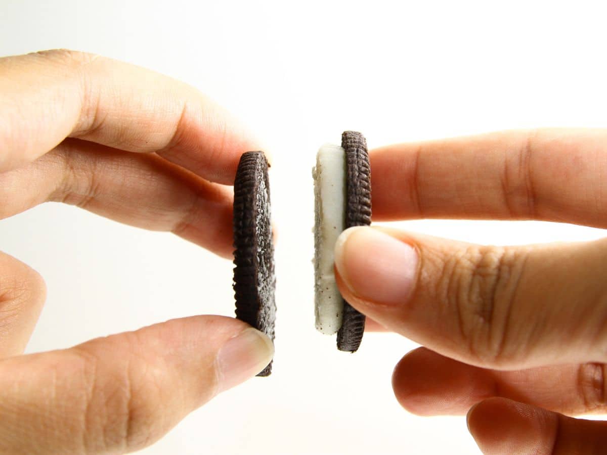 Hands taking apart oreo cookies.