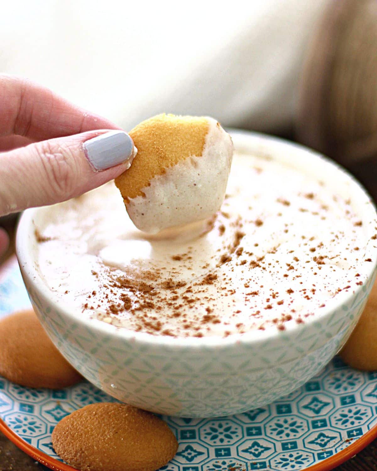 A vanilla wafter dipping into eggnog dip.