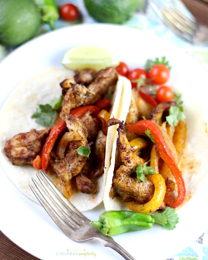 Sheet Pan Chicken Fajitas in a flour tortilla on a white plate topped with cilantro.