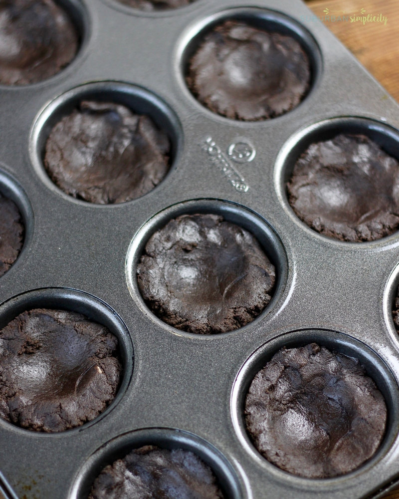 Dark chocolate cookie cup dough pressed into a cupcake pan ready to be put in the oven.