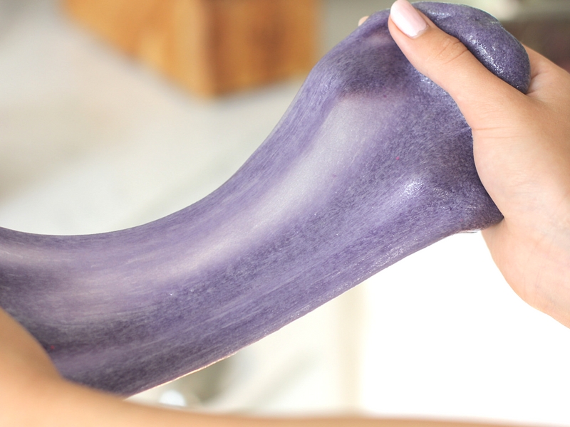 Purple slime being stretched by a girls hands.