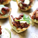 Mini Chicken chipotle tostadas on a serving platter garnished with cilantro and lime.