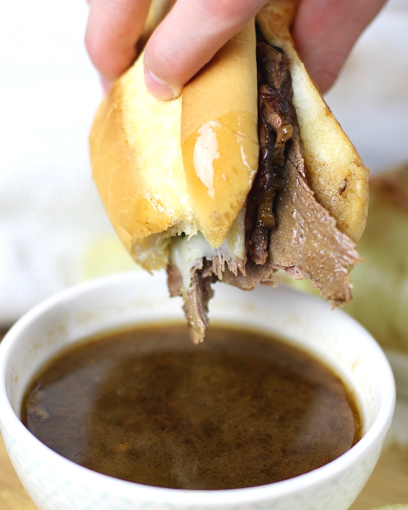 French Dip Sandwich being dipped in the au jus sauce.