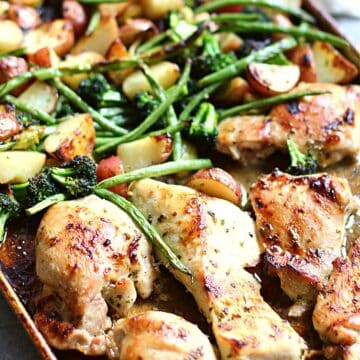 Baking pan with honey garlic chicken, veggies, and potatoes on it.