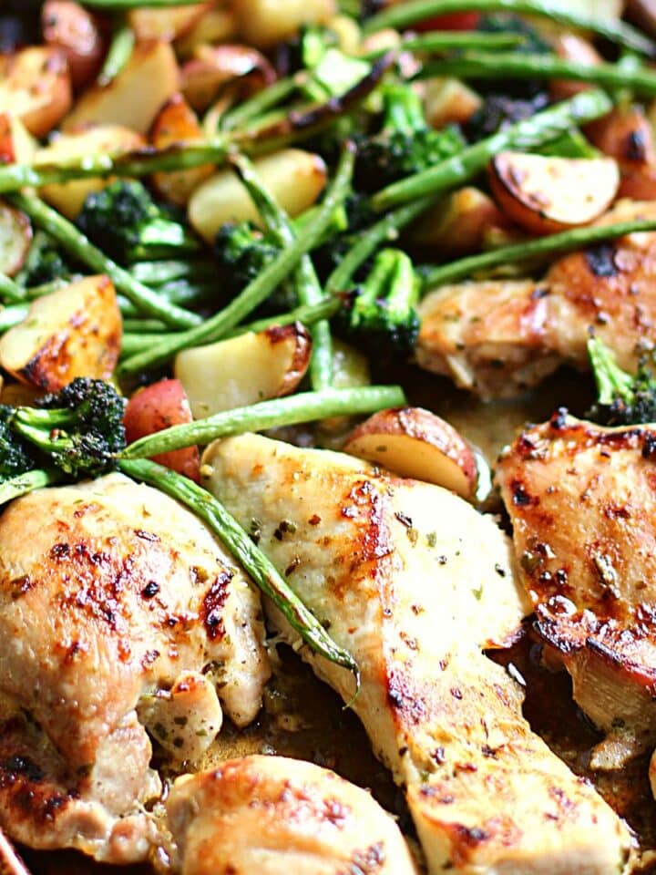 Baking pan with honey garlic chicken, veggies, and potatoes on it.