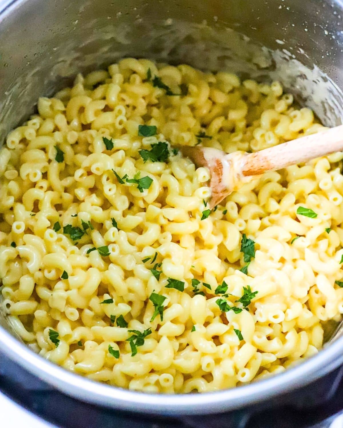 Finished creamy instant pot mac and cheese in the pot with a wooden spoon.