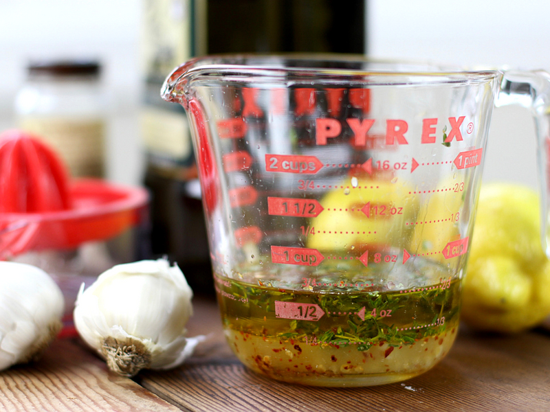 measuring cup with olive oil with a garlic clove next to it.