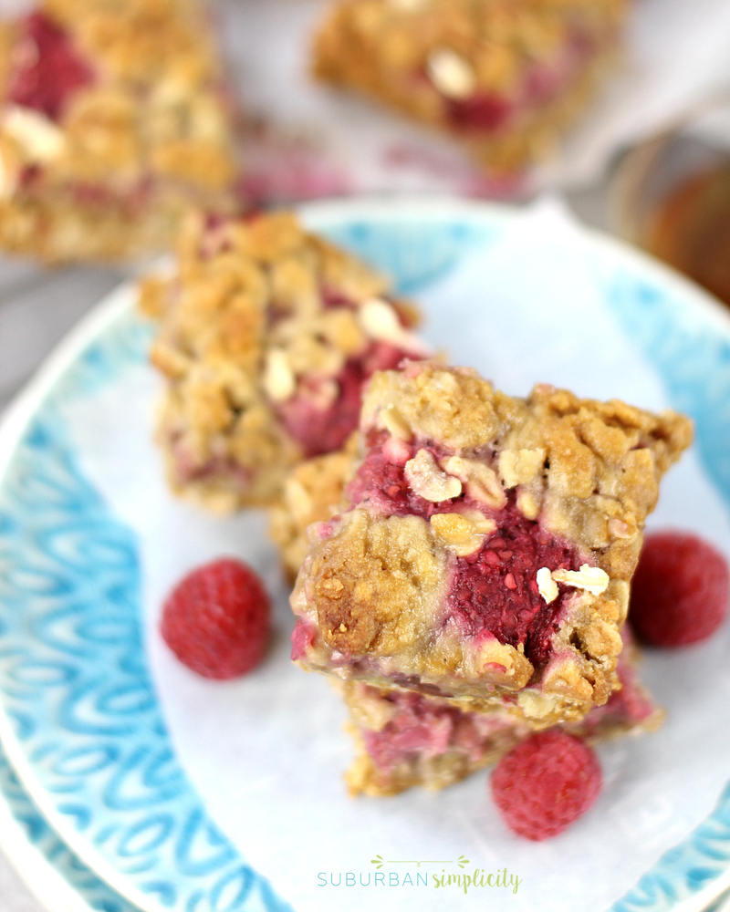 Raspberry oatmeal bars on a plate with fresh raspberries