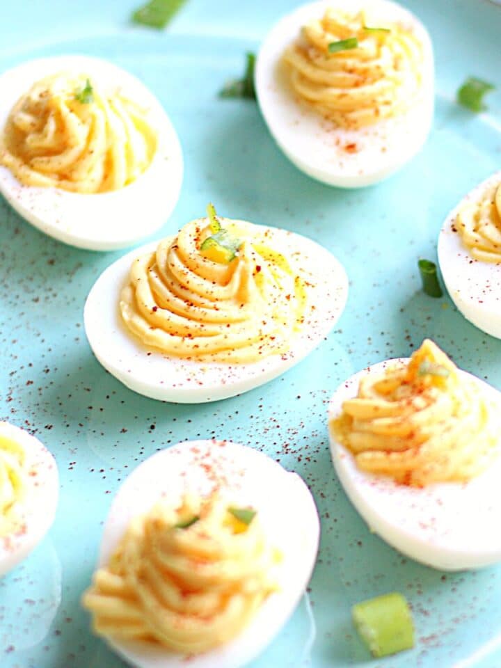 Deviled eggs topped with paprika on a plate.