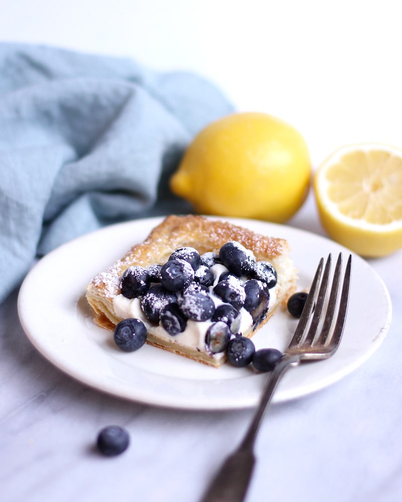 Blueberry tart on a plate with a fork.