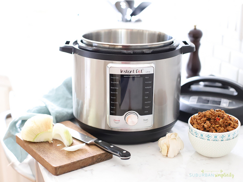 Instant pot on the counter with ingredients to make dinner.