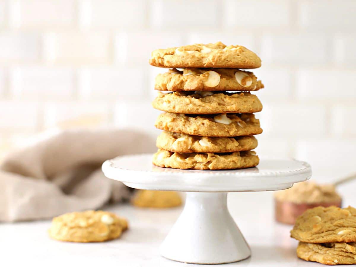 A stack of pumpkin cookies on a cake stand.