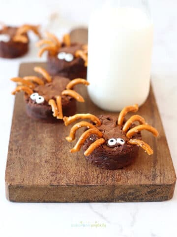 Brownie Spiders on a cutting board with milk.