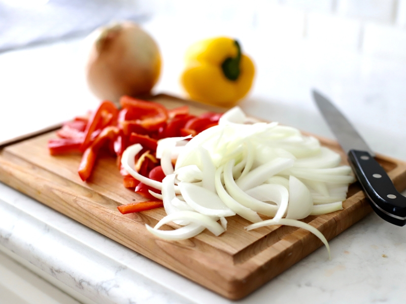 Sliced Peppers and onions on a cutting board.