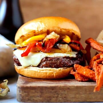 Cheesesteak burger with french fries next to it.