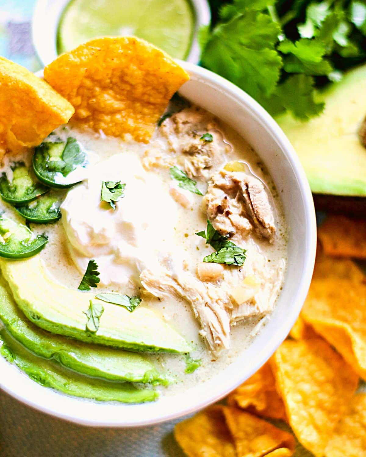 White chicken chili in a bowl with herbs on top.