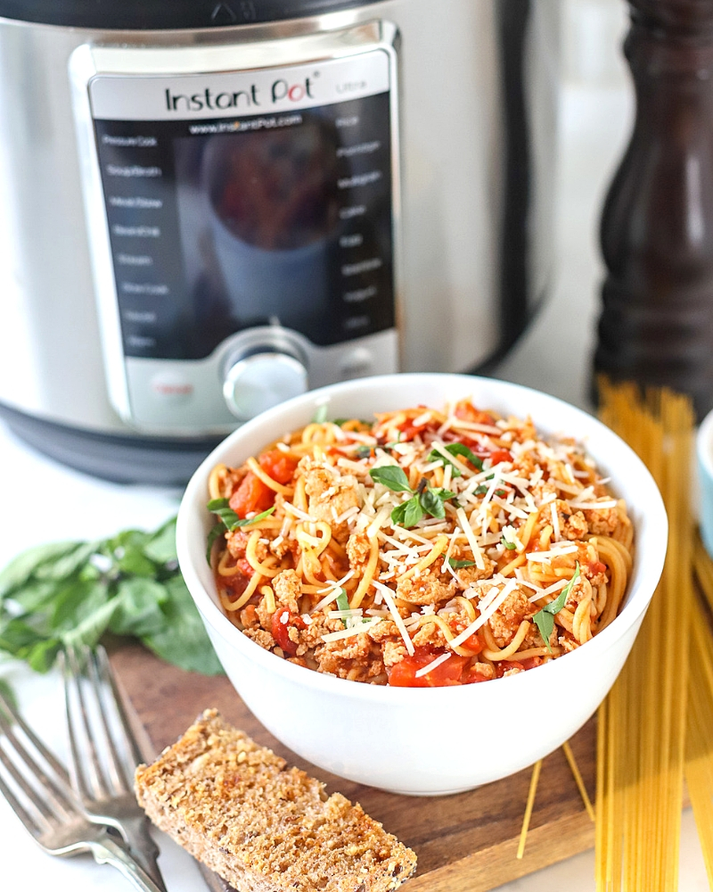 Instant Pot Spaghetti and meat sauce in a bowl with garlic bread next to it.