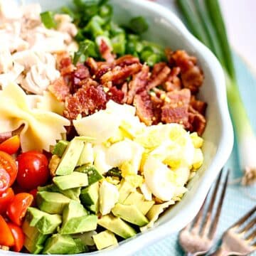 Cobb pasta salad in a blue bowl with forks next to it.