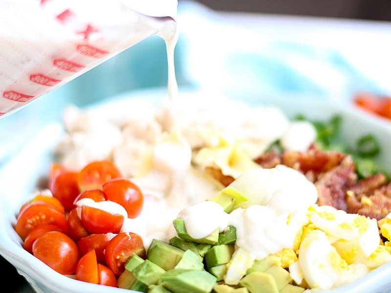 Cobb Pasta Salad with dressing being poured over it.