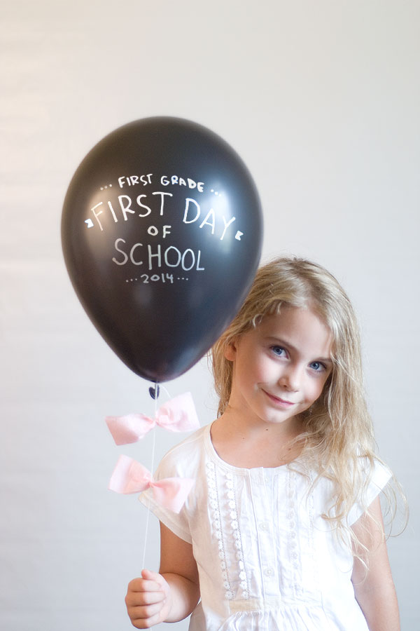 A little girl posing for a picture with a balloon