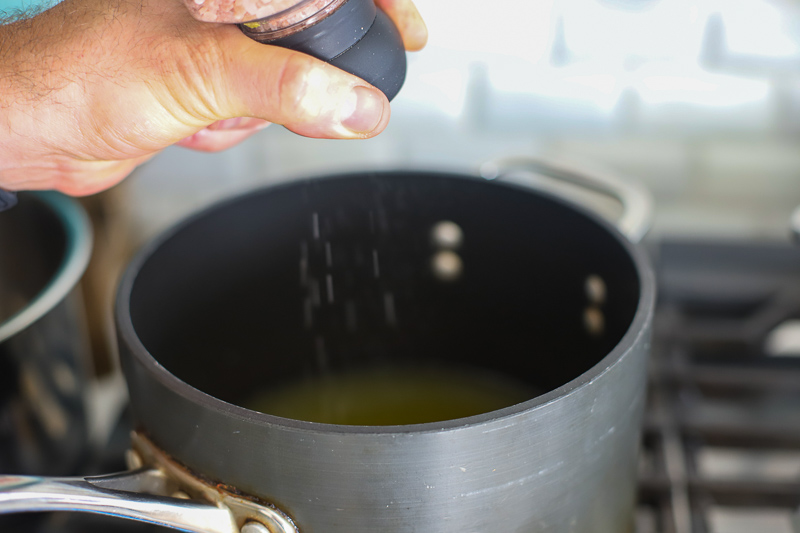 salt being added to pot to make quinoa