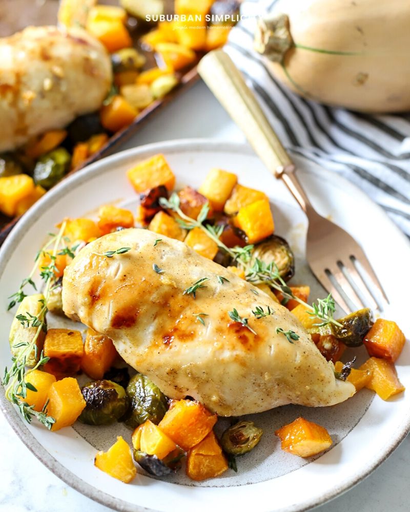 Healthy sheet pan chicken and butternut squash on a plate with fresh thyme