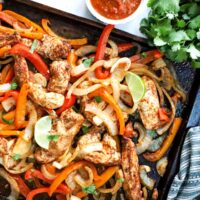 Chicken with peppers and onions cooked on a sheet pan.