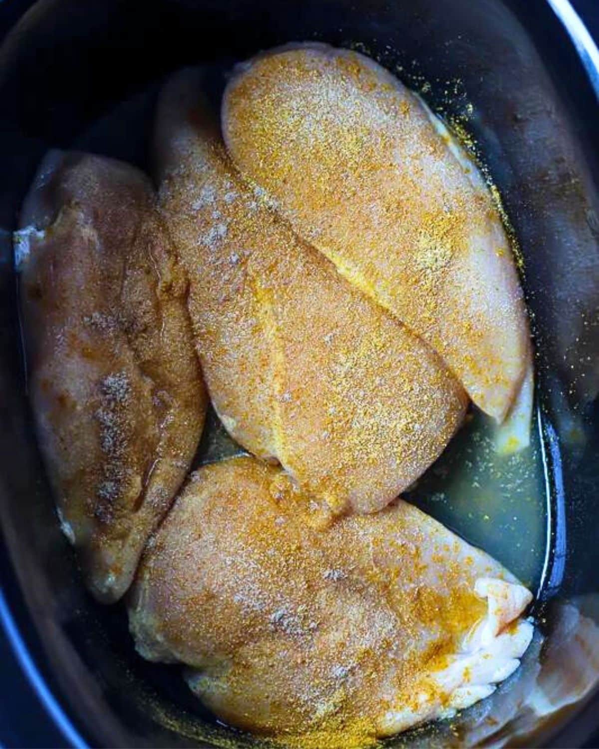 Crock Pot filled with seasoned chicken.