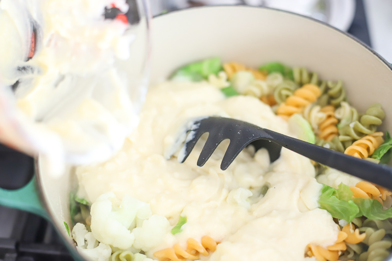 Cheese sauce being poured over a pot of macaroni