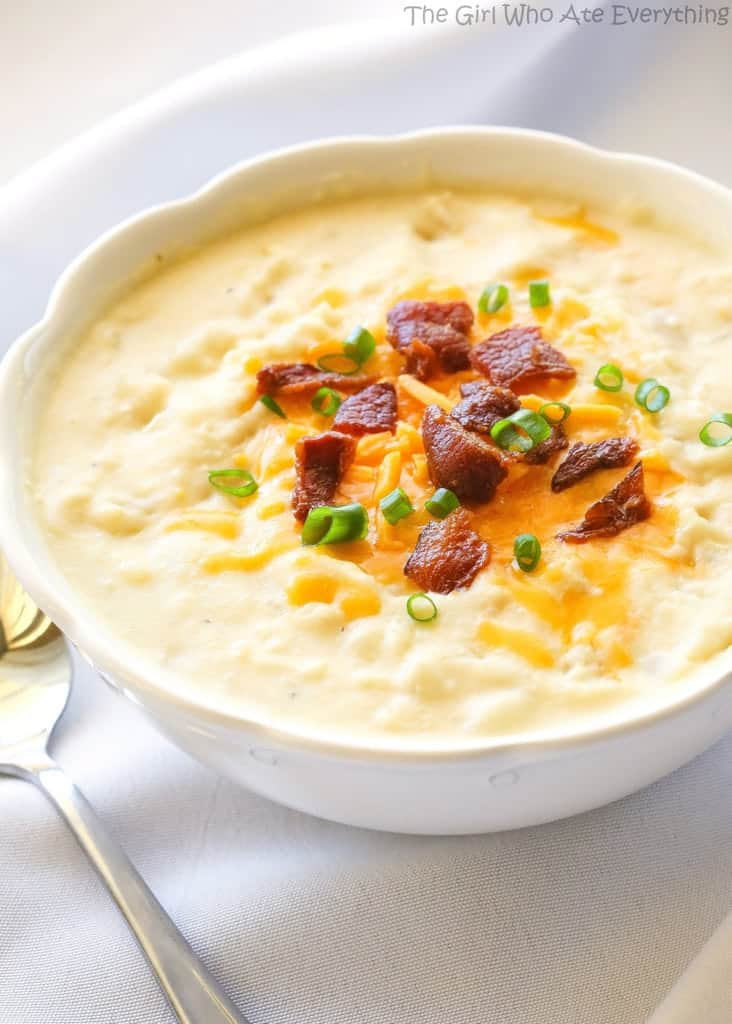 Potato soup in a bowl topped with bacon and chives.