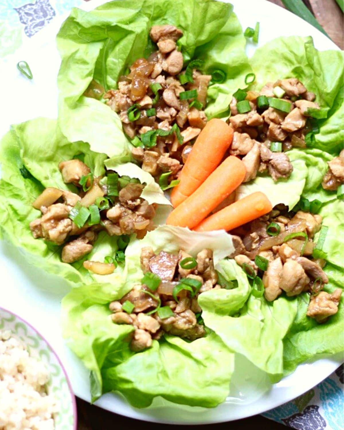 Asian lettuce wraps on a plate with carrots.