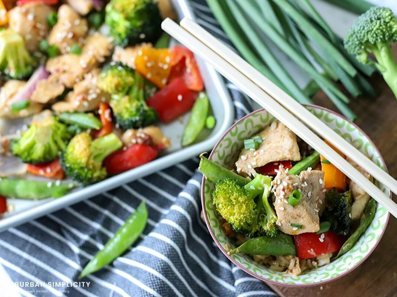 Bowl of sesame chicken and vegetables with chopsticks