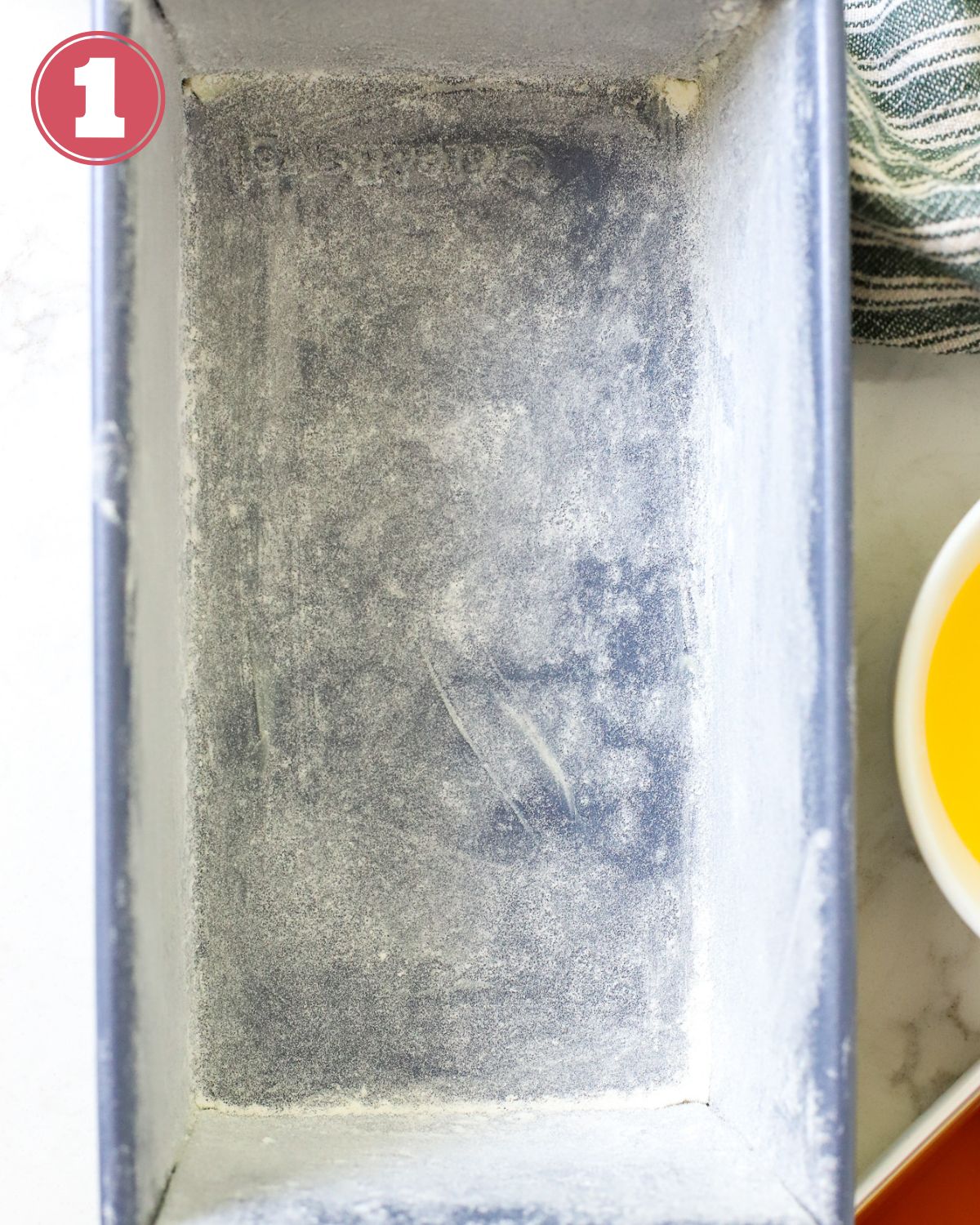 Loaf pan with grease and flour for baking.