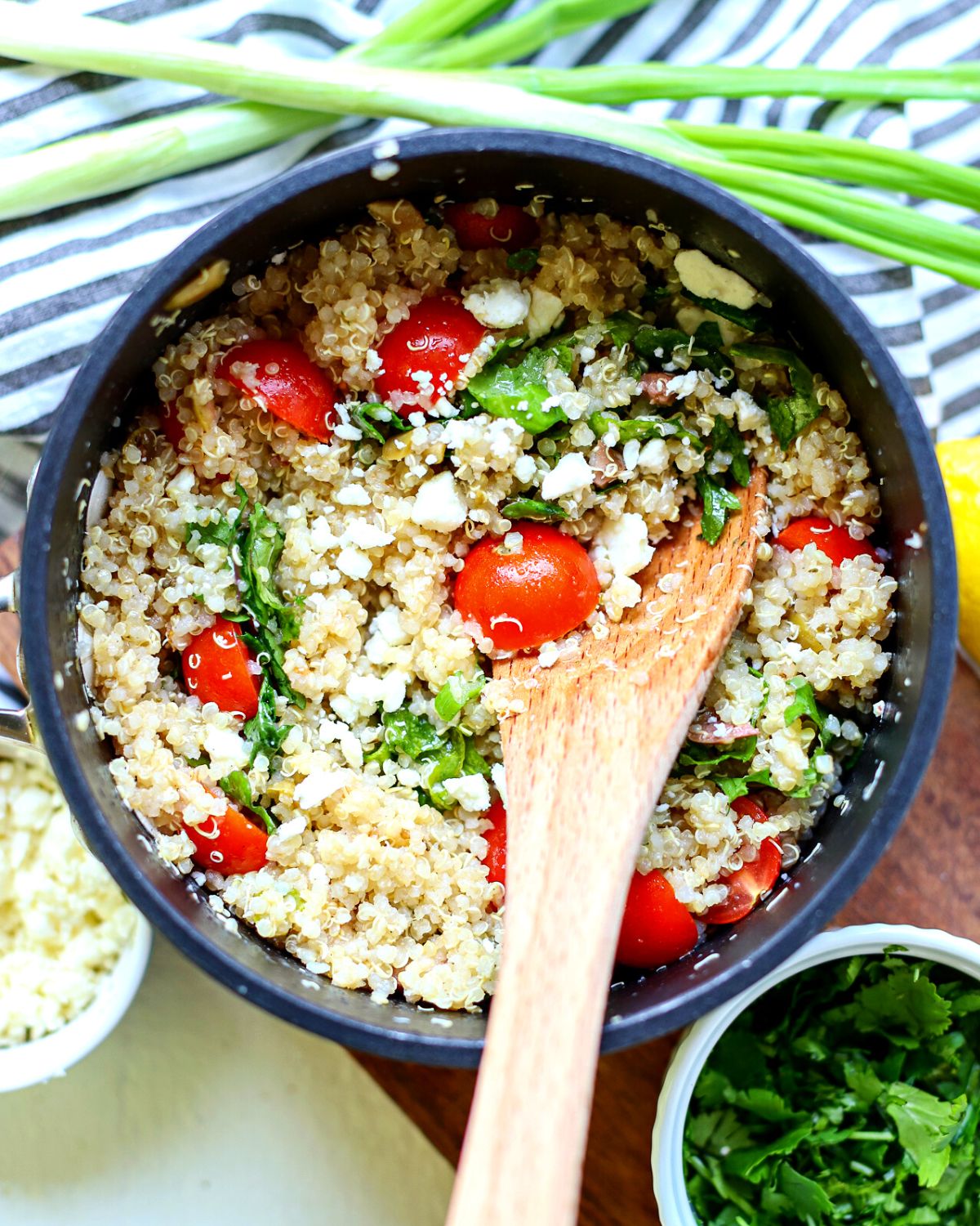 Pot full of quinoa salad with tomatoes and kale.