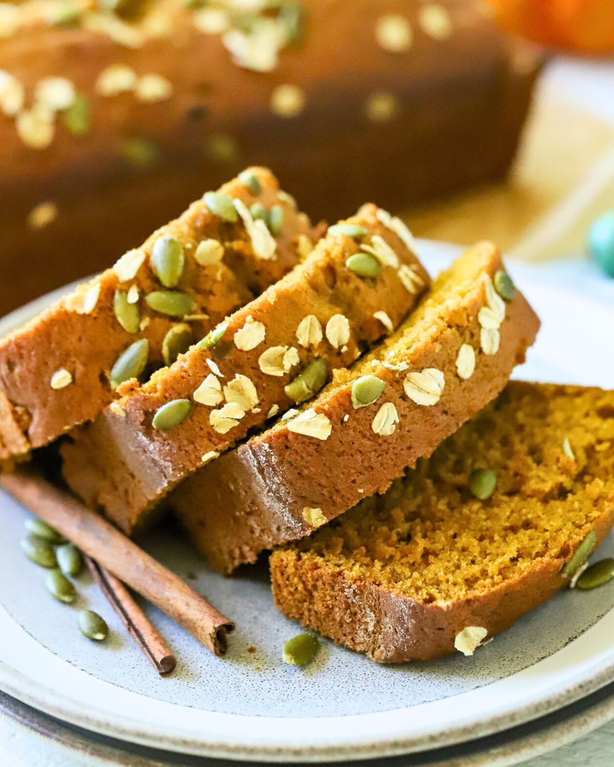 Sliced pumpkin bread with pumpkin seeds on top.