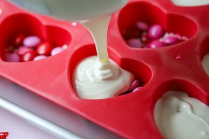 white chocolate being poured in a heart-shaped mold