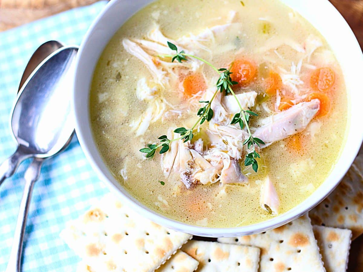 Bowl of homemade chicken soup with thyme on top.