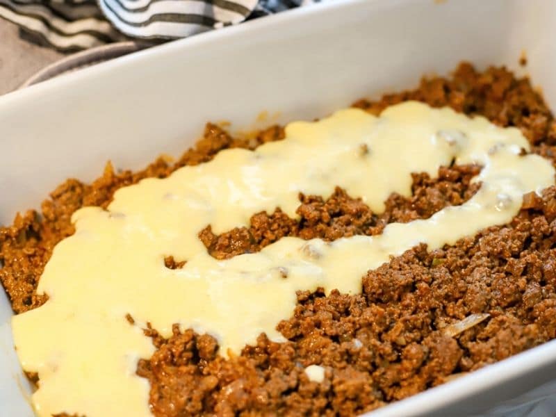 cheese sauce being poured into casserole