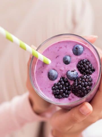 woman holding a smoothie with a straw