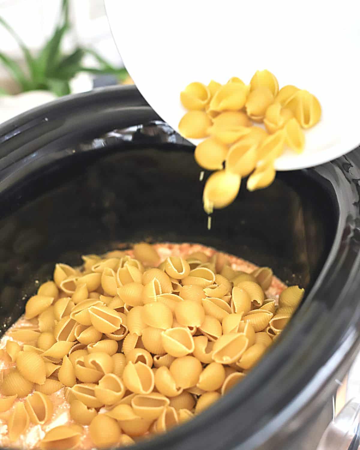 Pasta being added to crock pot.