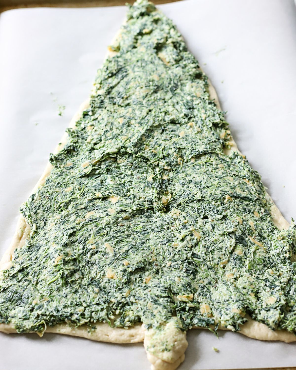 Pizza dough covered in spinach dip.