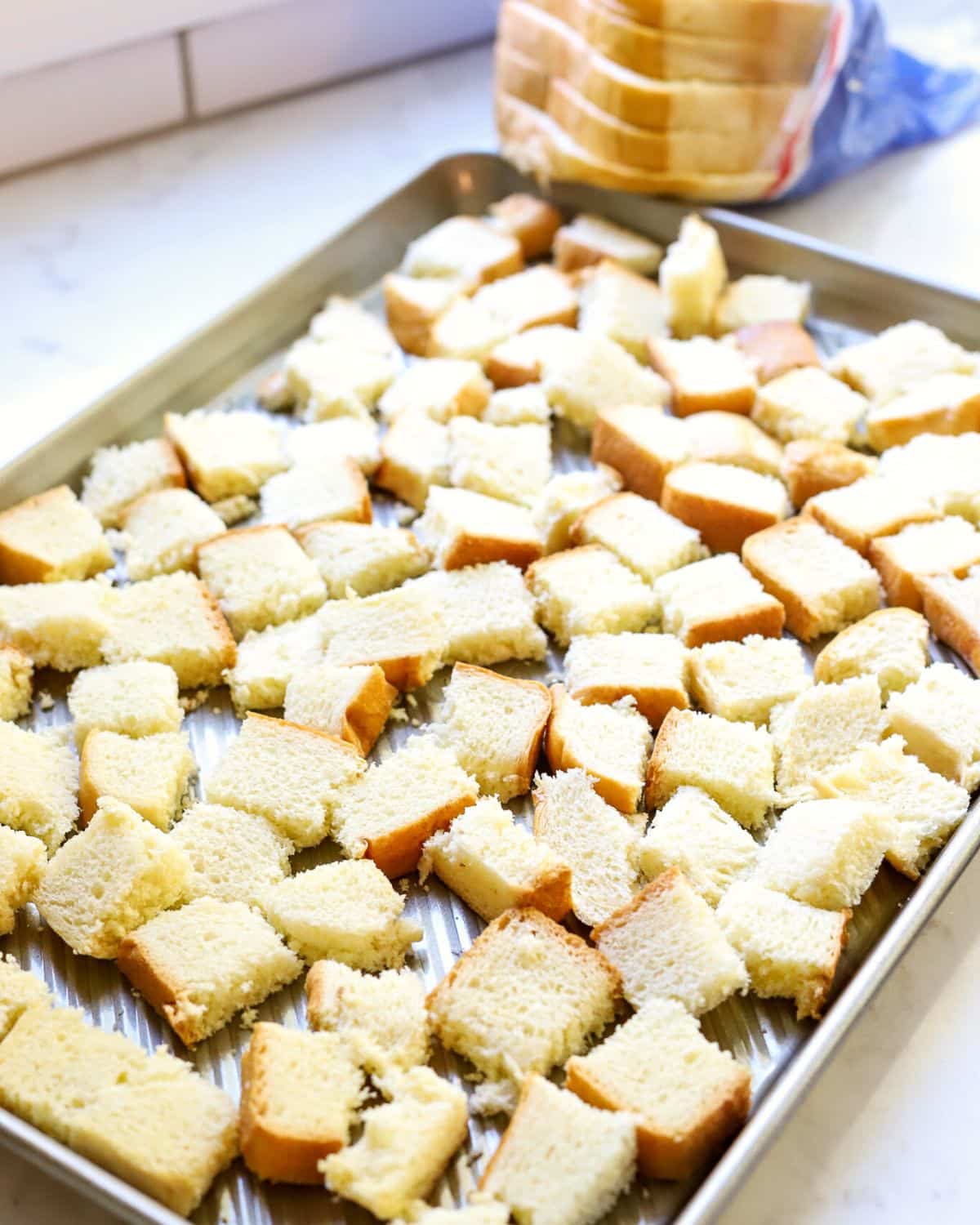 Cubed bread on a baking sheet.