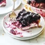 Slice of blueberry cream cheese pie with a bite out of it on a plate.