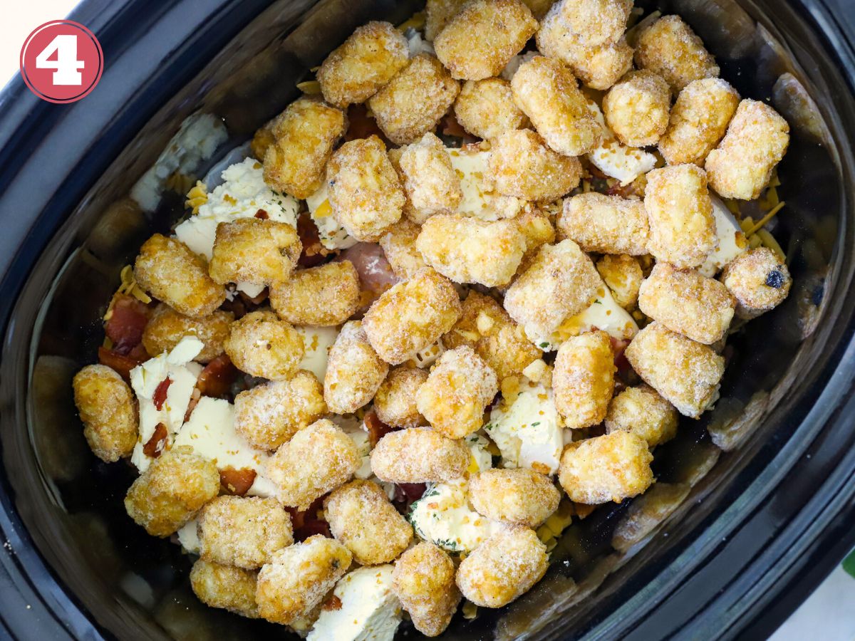 A layered tater tot casserole with chicken in a slow cooker.